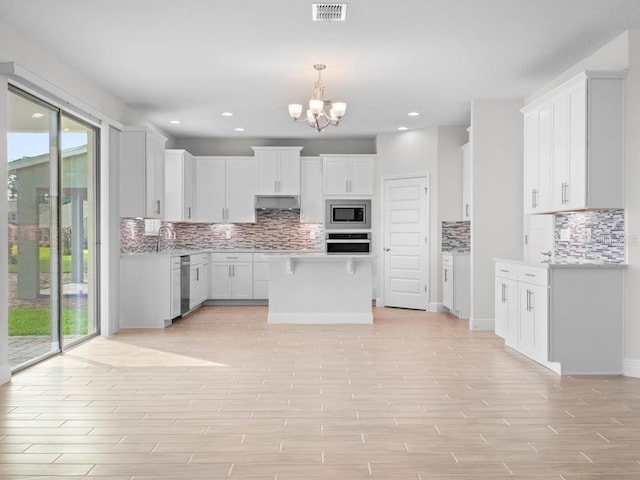 11027 Hollow Bay Dr, Winter Garden, FL 34787 - kitchen featuring stainless steel appliances, decorative backsplash, a chandelier, light wood-style floors, and light countertops