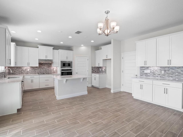 11027 Hollow Bay Dr, Winter Garden, FL 34787 - kitchen featuring appliances with stainless steel finishes, a sink, decorative backsplash, under cabinet range hood, and recessed lighting