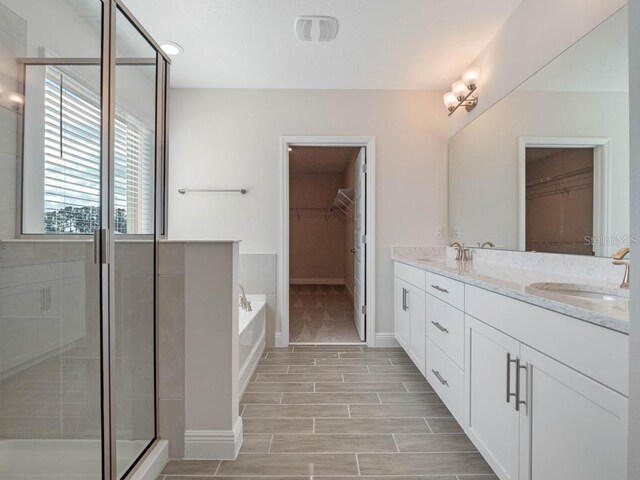 11027 Hollow Bay Dr, Winter Garden, FL 34787 - bathroom featuring a walk in closet, double vanity, a garden tub, and a shower stall
