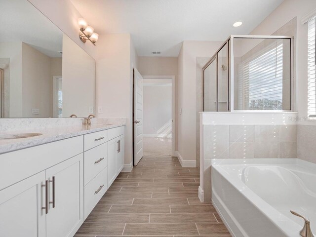 11027 Hollow Bay Dr, Winter Garden, FL 34787 - full bathroom with a garden tub, double vanity, a shower stall, wood tiled floors, and baseboards
