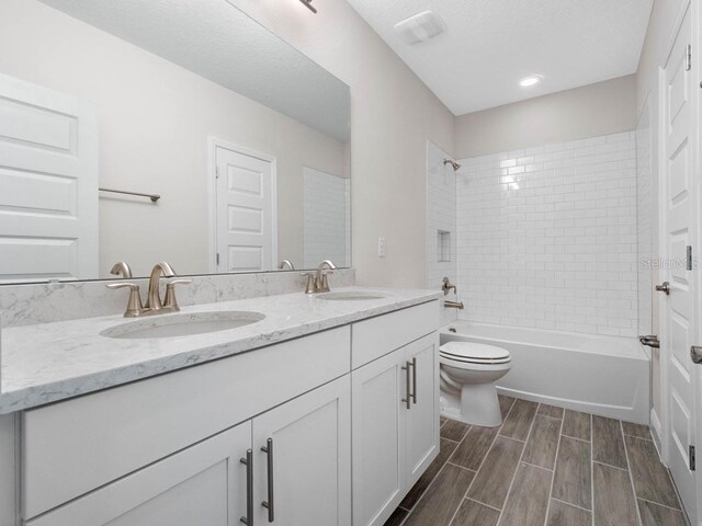 11027 Hollow Bay Dr, Winter Garden, FL 34787 - full bathroom featuring double vanity, toilet,  shower combination, and wood finished floors