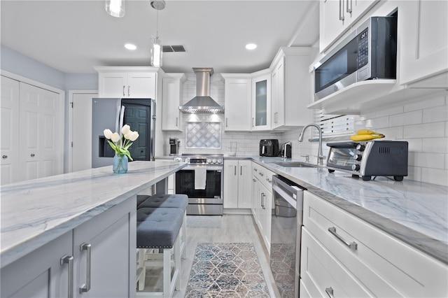 938 Southridge Trl, Altamonte Springs, FL 32714 - kitchen with appliances with stainless steel finishes, wall chimney exhaust hood, a sink, white cabinetry, and decorative backsplash