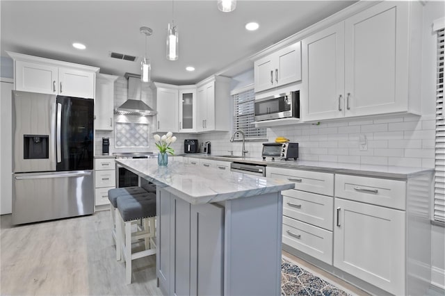 938 Southridge Trl, Altamonte Springs, FL 32714 - kitchen featuring stainless steel appliances, wall chimney exhaust hood, light wood-style flooring, white cabinets, and a kitchen island