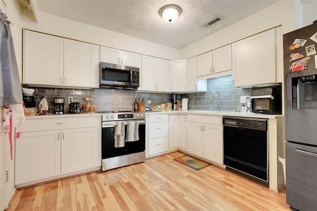 5323 Hansel Ave Unit E14, Orlando, FL 32809 - kitchen featuring stainless steel appliances, a sink, light countertops, light wood-style flooring, and tasteful backsplash