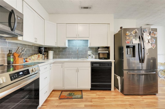 5323 Hansel Ave Unit E14, Orlando, FL 32809 - kitchen with stainless steel appliances, a sink, light wood-style floors, white cabinetry, and a textured ceiling