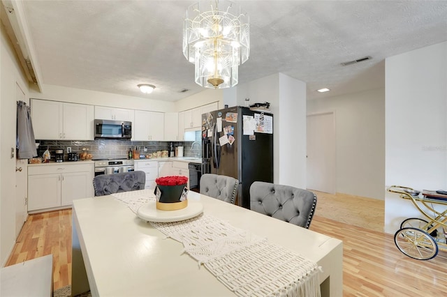 5323 Hansel Ave Unit E14, Orlando, FL 32809 - dining room with light wood finished floors, a chandelier, and a textured ceiling