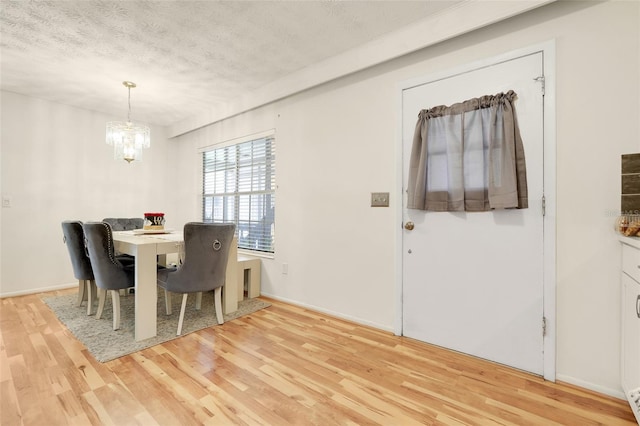 5323 Hansel Ave Unit E14, Orlando, FL 32809 - dining space featuring light wood-style flooring, a chandelier, a textured ceiling, and baseboards