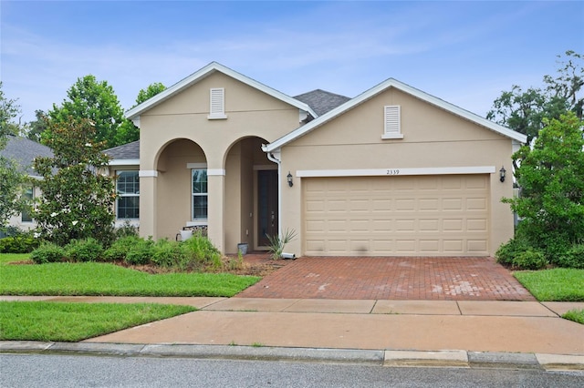 2339 Jernigan Loop, Kissimmee, FL 34746 - traditional-style home featuring stucco siding, decorative driveway, a garage, and a front yard