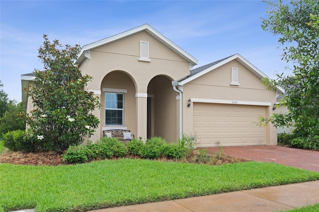 2339 Jernigan Loop, Kissimmee, FL 34746 - view of front facade featuring stucco siding, a front lawn, an attached garage, and decorative driveway