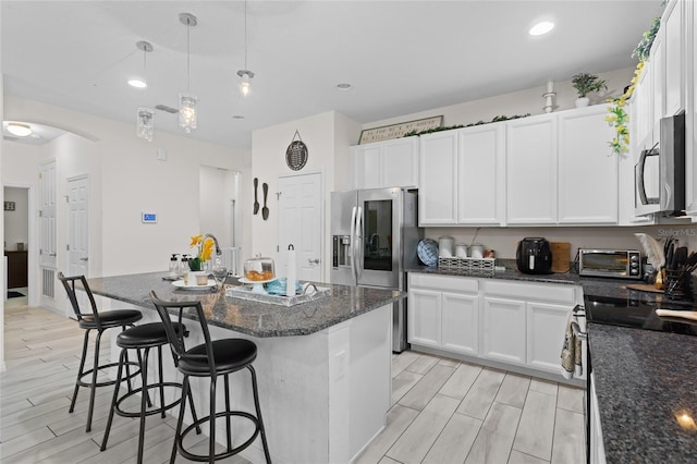 2339 Jernigan Loop, Kissimmee, FL 34746 - kitchen with appliances with stainless steel finishes, wood tiled floors, a kitchen breakfast bar, white cabinets, and recessed lighting