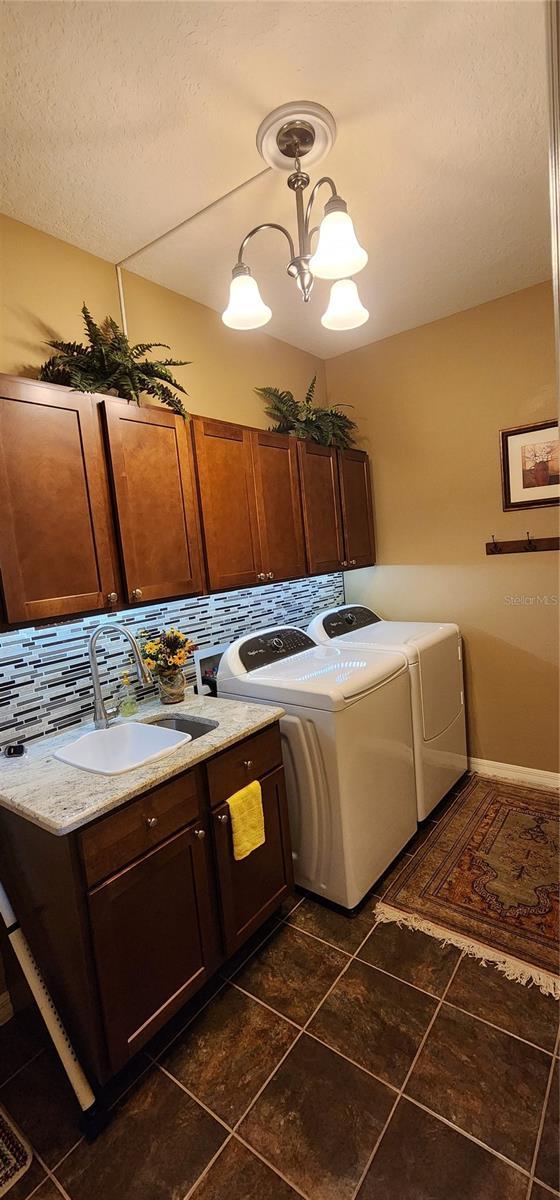 7620 Tangle Rush Dr, Gibsonton, FL 33534 - laundry room featuring cabinet space, separate washer and dryer, dark tile patterned floors, and a textured ceiling