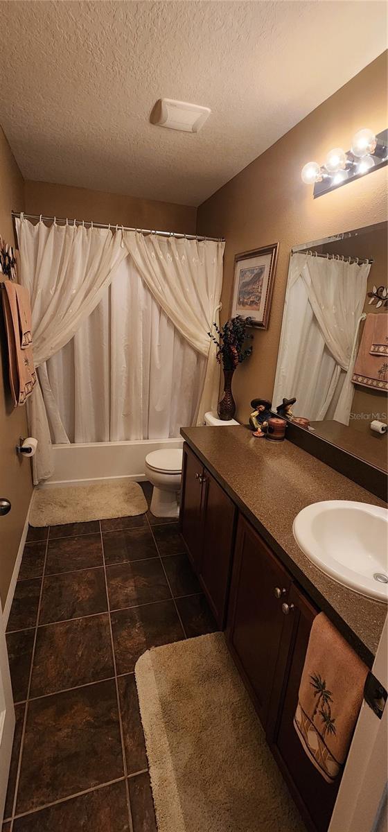 7620 Tangle Rush Dr, Gibsonton, FL 33534 - full bath with vanity, toilet, shower / bath combination with curtain, tile patterned floors, and a textured ceiling