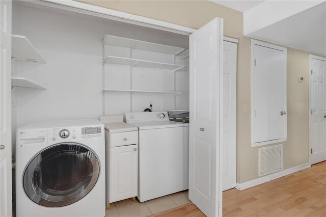 5662 Royal Pine Blvd Unit 24, Orlando, FL 32807 - laundry area featuring washer and dryer, light wood finished floors, cabinet space, and baseboards