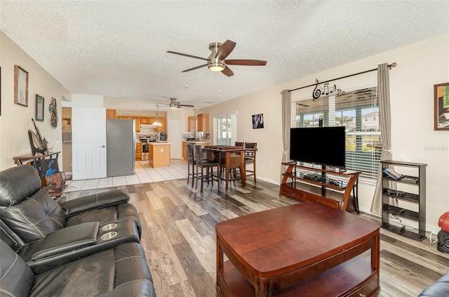 16012 Lanesboro Ct, Clermont, FL 34711 - living room featuring a textured ceiling, ceiling fan, light wood-style flooring, and baseboards