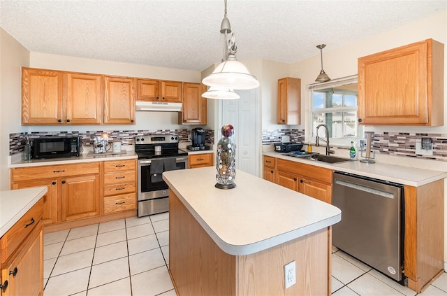 16012 Lanesboro Ct, Clermont, FL 34711 - kitchen featuring appliances with stainless steel finishes, under cabinet range hood, a sink, tasteful backsplash, and light countertops