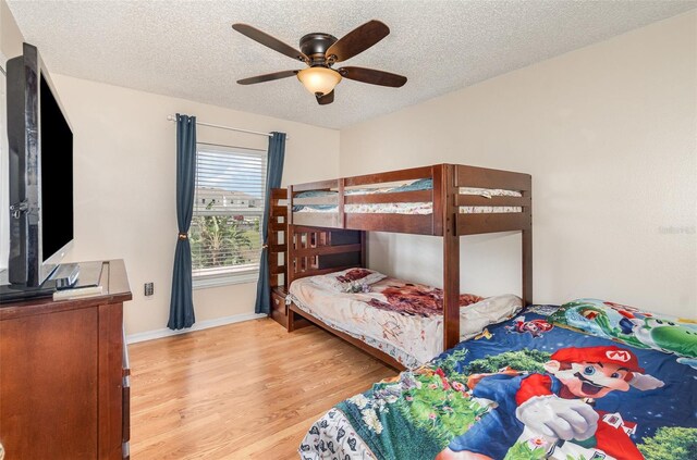 16012 Lanesboro Ct, Clermont, FL 34711 - bedroom featuring light wood-style flooring, a textured ceiling, ceiling fan, and baseboards