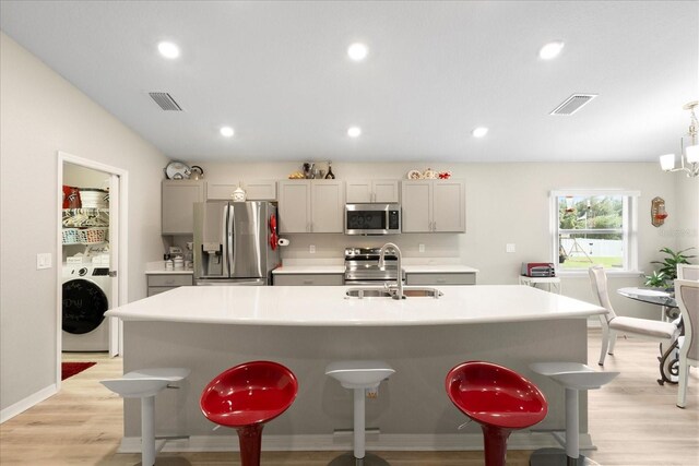 9020 SE 42nd Ct, Ocala, FL 34480 - kitchen with appliances with stainless steel finishes, washer / clothes dryer, a kitchen breakfast bar, light wood finished floors, and recessed lighting