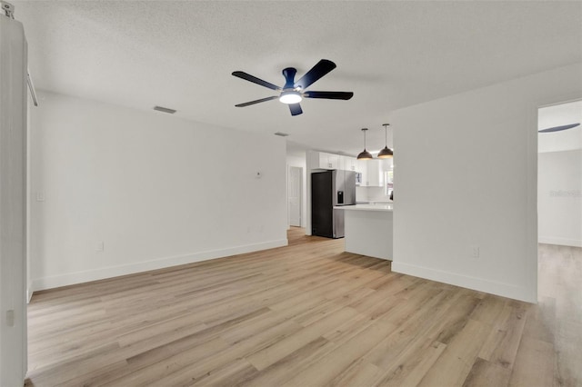 324 James Pl, Saint Cloud, FL 34769 - unfurnished living room featuring light wood-type flooring, a ceiling fan, baseboards, and a textured ceiling