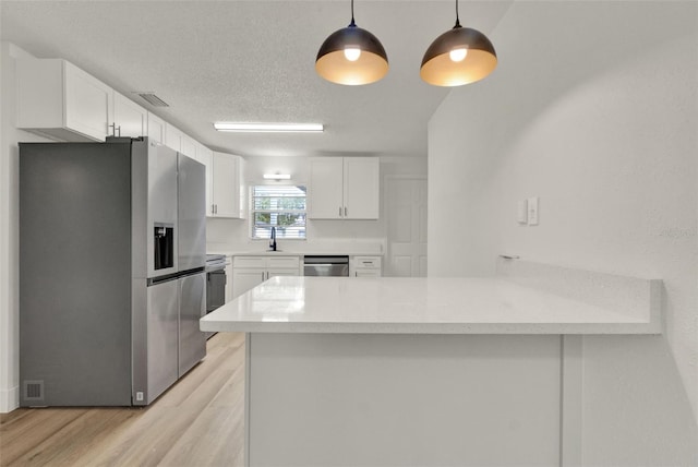 324 James Pl, Saint Cloud, FL 34769 - kitchen featuring stainless steel appliances, a peninsula, light wood-style floors, a sink, and white cabinetry