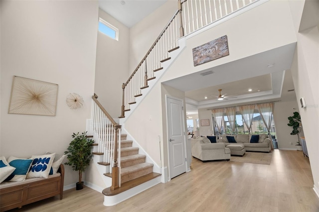 7163 Talamore Dr, Wesley Chapel, FL 33545 - foyer with wood finished floors, stairs, ceiling fan, a tray ceiling, and baseboards