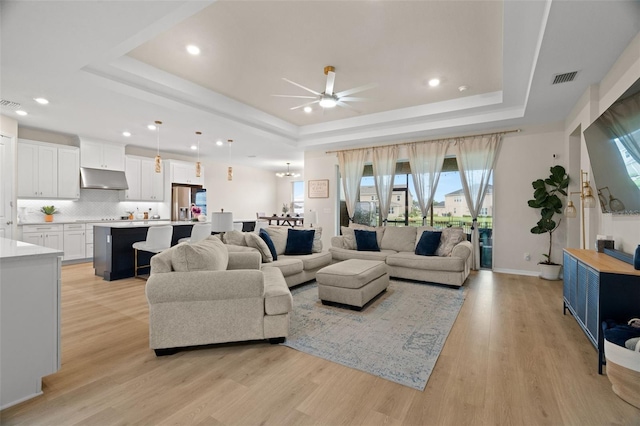 7163 Talamore Dr, Wesley Chapel, FL 33545 - living room with a tray ceiling, a ceiling fan, healthy amount of natural light, light wood-style flooring, and recessed lighting