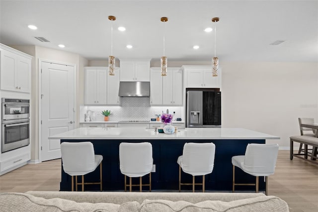 7163 Talamore Dr, Wesley Chapel, FL 33545 - kitchen with refrigerator with ice dispenser, an island with sink, light wood-style floors, light countertops, and recessed lighting