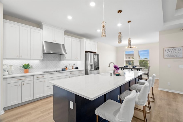 7163 Talamore Dr, Wesley Chapel, FL 33545 - kitchen featuring under cabinet range hood, stainless steel fridge with ice dispenser, backsplash, light wood-style flooring, and recessed lighting