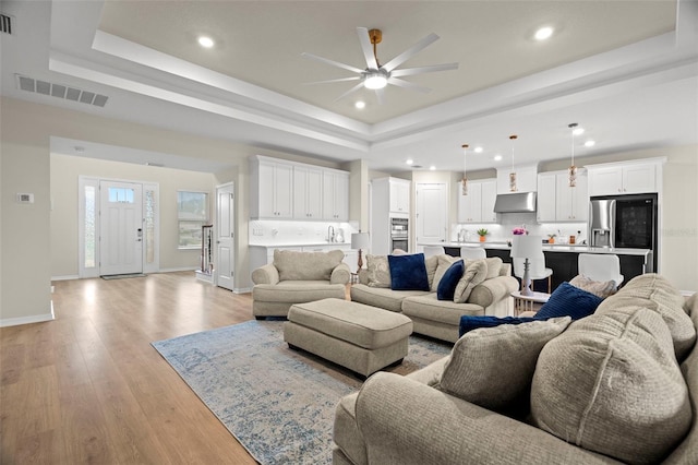 7163 Talamore Dr, Wesley Chapel, FL 33545 - living room with a raised ceiling, a ceiling fan, recessed lighting, light wood-style flooring, and baseboards