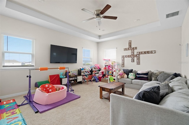 7163 Talamore Dr, Wesley Chapel, FL 33545 - carpeted living room featuring a raised ceiling, ceiling fan, and baseboards