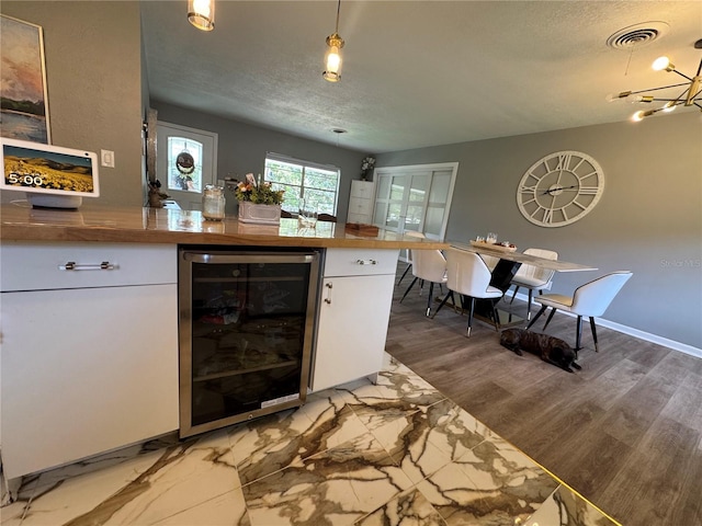 3702 Mirror Lake Dr, Apopka, FL 32703 - kitchen with beverage cooler, white cabinets, a textured ceiling, light wood-style flooring, and a chandelier