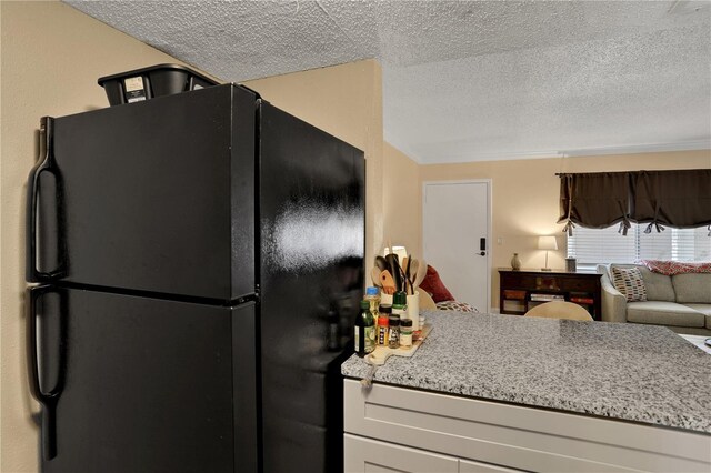 145 Oyster Bay Cir Unit 140, Altamonte Springs, FL 32701 - kitchen featuring freestanding refrigerator, a textured ceiling, light stone countertops, and open floor plan