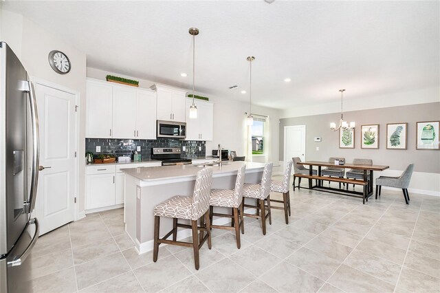 9106 Cut Shot Dr, Winter Garden, FL 34787 - kitchen with stainless steel appliances, light tile patterned flooring, backsplash, a chandelier, and an island with sink