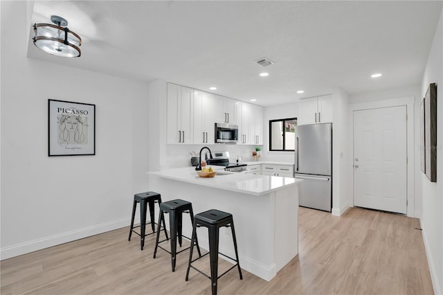 2541 Leeward Way, Winter Park, FL 32792 - kitchen featuring appliances with stainless steel finishes, a peninsula, a kitchen breakfast bar, light countertops, and light wood-type flooring