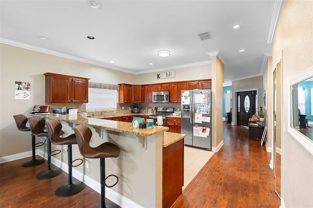 2017 W Gore St, Orlando, FL 32805 - kitchen with stainless steel appliances, a peninsula, a breakfast bar area, light stone countertops, and decorative backsplash