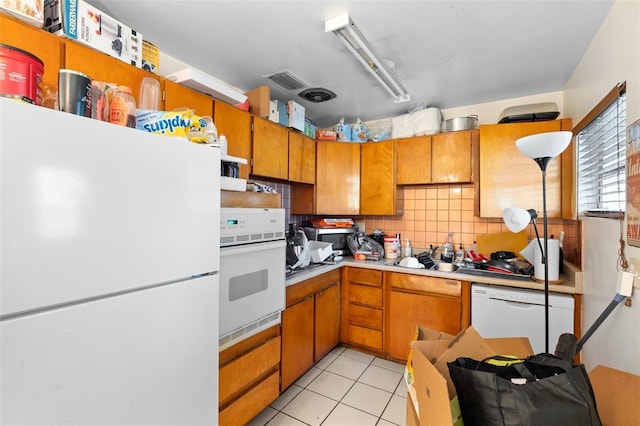 2044 W Gore St, Orlando, FL 32805 - kitchen featuring white appliances, decorative backsplash, brown cabinets, light countertops, and light tile patterned floors