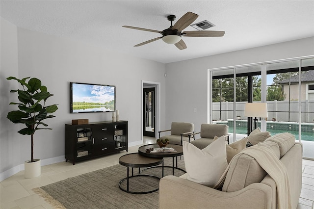 201 Hammock Dunes Pl, Orlando, FL 32828 - tiled living room with ceiling fan, a textured ceiling, and baseboards
