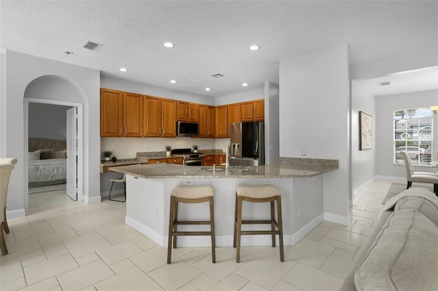 201 Hammock Dunes Pl, Orlando, FL 32828 - kitchen featuring stainless steel appliances, a sink, a peninsula, a breakfast bar area, and light stone countertops