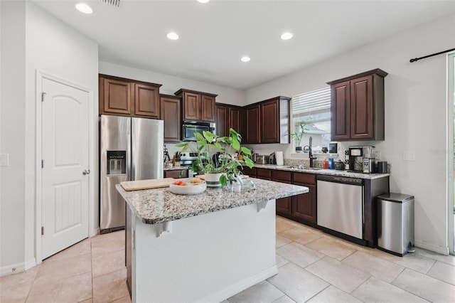 16440 Centipede St, Clermont, FL 34714 - kitchen featuring stainless steel appliances, dark brown cabinetry, recessed lighting, light stone counters, and a kitchen island