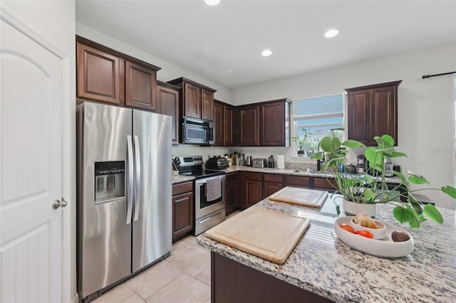 16440 Centipede St, Clermont, FL 34714 - kitchen with appliances with stainless steel finishes, dark brown cabinets, light tile patterned floors, recessed lighting, and light stone counters