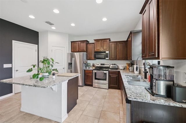 16440 Centipede St, Clermont, FL 34714 - kitchen with stainless steel appliances, a kitchen island, light stone counters, a kitchen breakfast bar, and recessed lighting