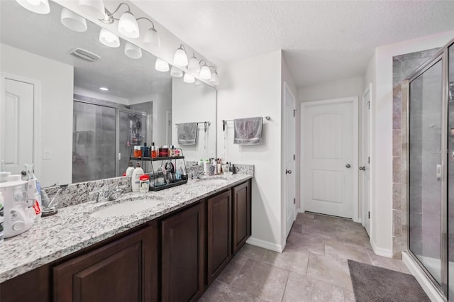 16440 Centipede St, Clermont, FL 34714 - full bath with double vanity, a stall shower, a textured ceiling, and tile patterned floors