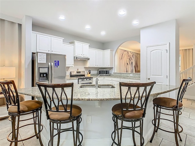5255 Wildwood Way, Davenport, FL 33837 - kitchen featuring stainless steel appliances, a sink, arched walkways, white cabinets, and light tile patterned floors