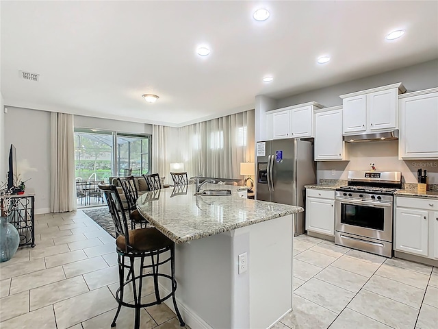 5255 Wildwood Way, Davenport, FL 33837 - kitchen featuring stainless steel appliances, under cabinet range hood, a sink, a breakfast bar area, and light stone countertops