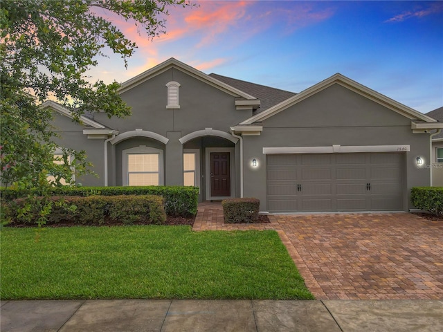 1540 Orange Valley Rdg, Ocoee, FL 34761 - view of front facade with stucco siding, a garage, a yard, and decorative driveway