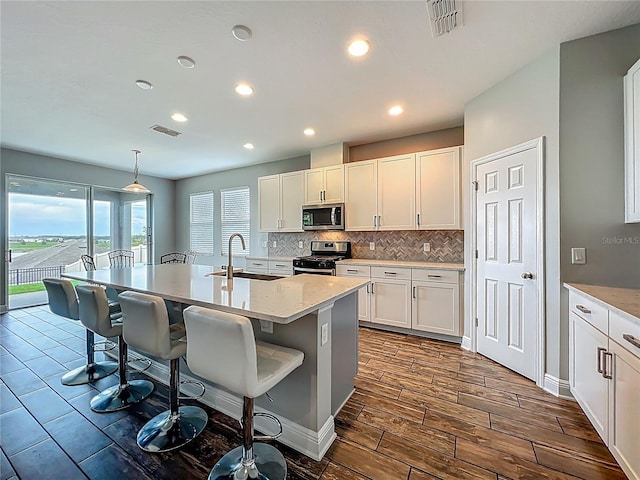 1540 Orange Valley Rdg, Ocoee, FL 34761 - kitchen featuring appliances with stainless steel finishes, a sink, decorative backsplash, a breakfast bar area, and white cabinetry
