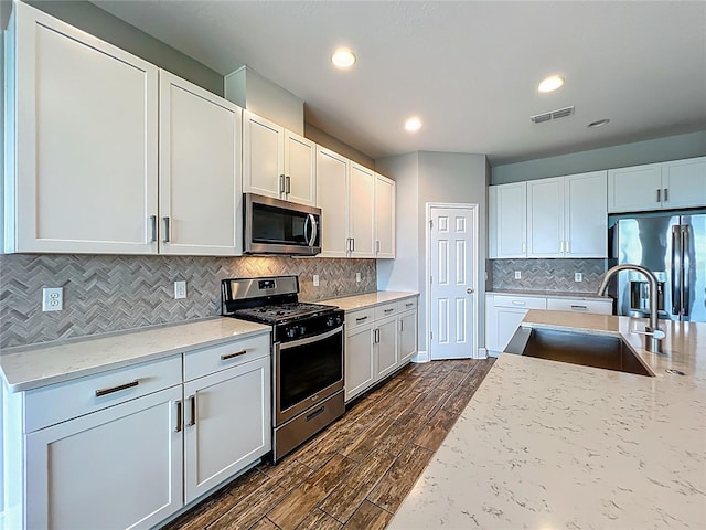 1540 Orange Valley Rdg, Ocoee, FL 34761 - kitchen featuring appliances with stainless steel finishes, a sink, dark wood-type flooring, backsplash, and light stone counters