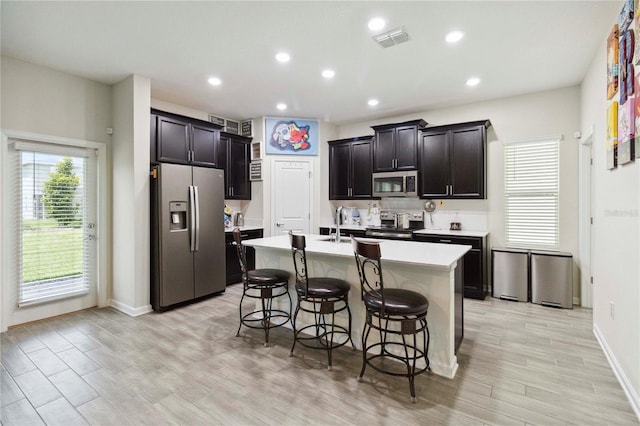 8975 Fluffy Lie Ct, Davenport, FL 33896 - kitchen featuring stainless steel appliances, a breakfast bar area, recessed lighting, light countertops, and light wood-type flooring