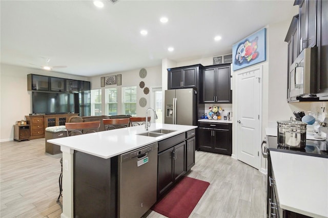 8975 Fluffy Lie Ct, Davenport, FL 33896 - kitchen featuring stainless steel appliances, a breakfast bar, light countertops, light wood-style flooring, and a center island with sink