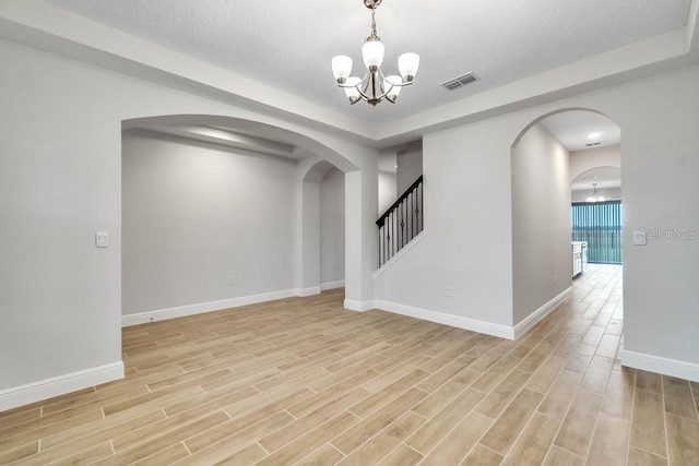 11063 Hollow Bay Dr, Winter Garden, FL 34787 - empty room featuring a chandelier, arched walkways, light wood-type flooring, baseboards, and a textured ceiling