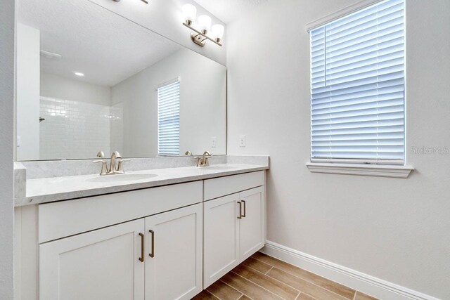 11063 Hollow Bay Dr, Winter Garden, FL 34787 - bathroom with double vanity, baseboards, wood finish floors, and tiled shower